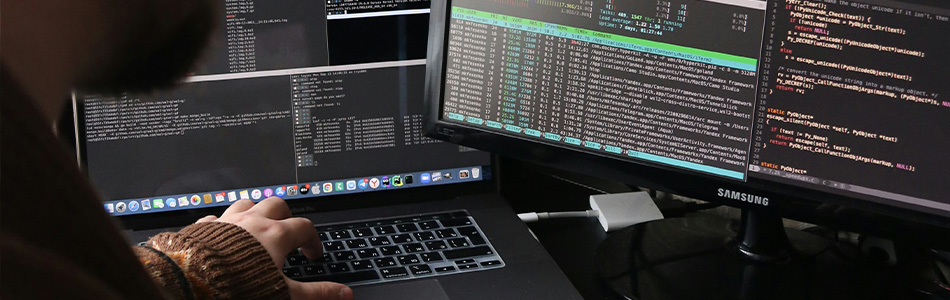 DevOps professional working on a laptop with multiple screens displaying code and system logs, representing DevOps consulting services.